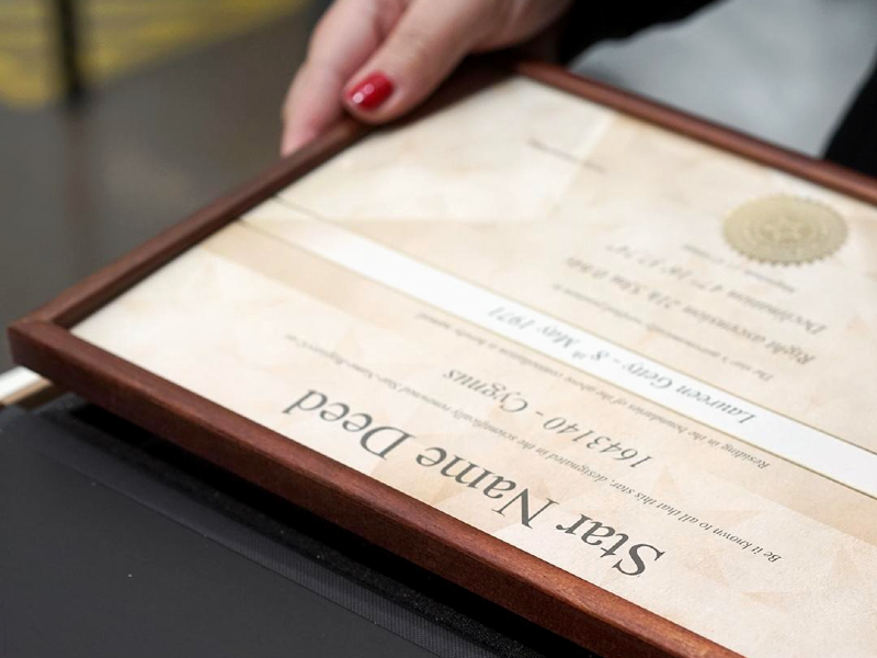 A close up of a framed certificate being put into a black box by a woman. The top of the certificate reads